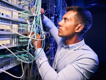 Technician installing fiber cables in data center rack